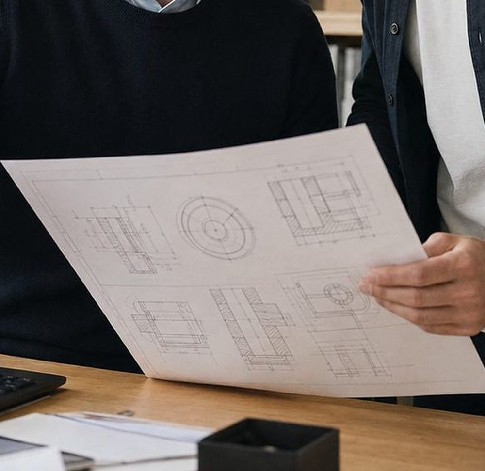 Technische Zeichnung in den Händen, im Hintergrund ein Büro